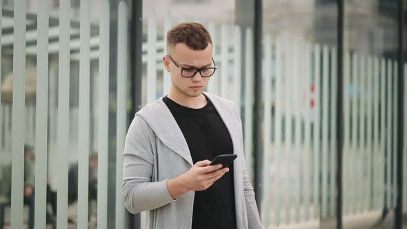 A Man is Standing at a Public Transport Stop and Looking Around