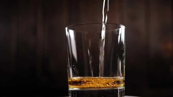 Close-up of Whiskey Poured Into a Rotating Glass on a Black Background
