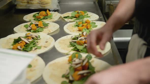 Closeup of Hands Preparing Vegetarian Wraps in a Restaurant Kitchen