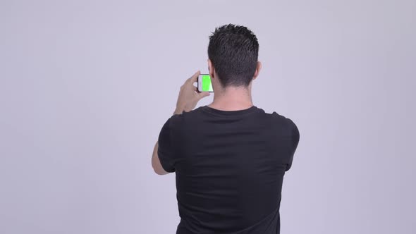 Rear View of Man Taking Picture with Phone Against White Background