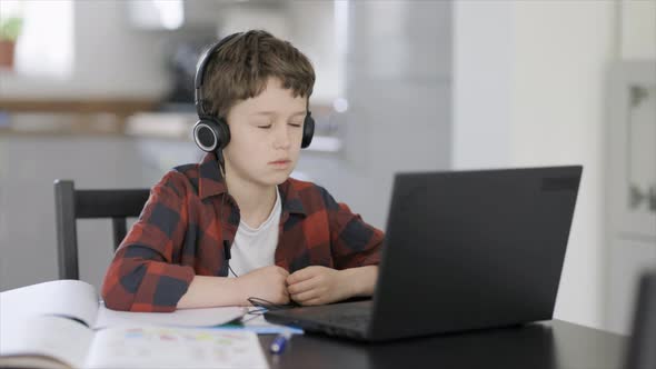 Tired boy listening to online class on laptop