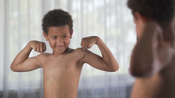 Confident Kid Looking at His Muscles in Mirror Imagining That He Is Super Hero