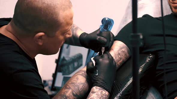 Male Tattoo Artist Tattooing a Client