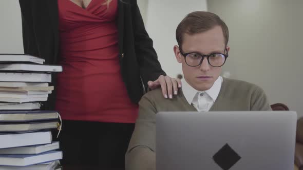 Young Modestly Dressed Man in Glasses Sitting at Table at Home, Working on Laptop