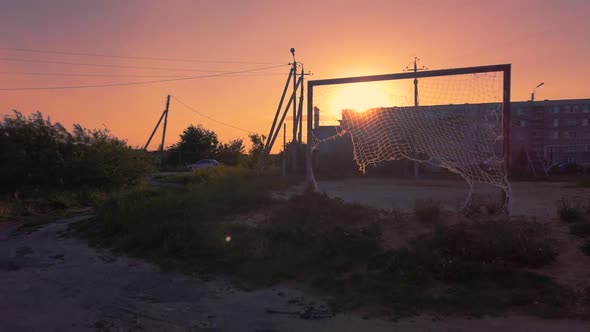 Passing by the football goal with torn net and living buildings in the background