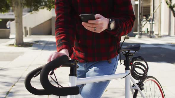 Albino african american man with bike using smartphone