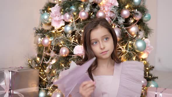 Beautiful Caucasian Girl Judges at the Christmas Tree in Pink Dress and Holds a Star