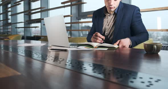 Concerned Man Working on Laptop Computer and Looking Away Thinking Solving Problem at Office