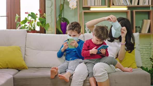 Young Mom with Her Two Sons on the Sofa Wearing