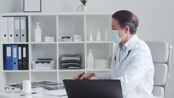 Professional medical doctor working in hospital office using computer technology.