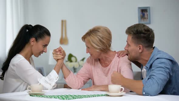 Man Supporting Mother During Arm Wrestling Competition With Wife, Family Battle