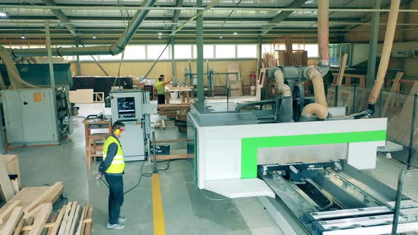 Male Technician Is Observing a Factory Machine Processing Wood