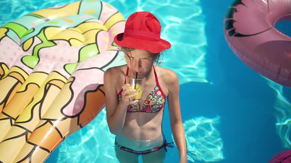 High Angle View Portrait of Slim Cute Caucasian Little Girl in Swimsuit and Red Hat Standing in Blue