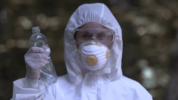 Woman in Protective Suit Holding Plastic Bottle, Urging to Reduce Reuse Recycle