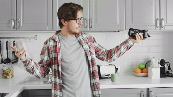 Young Attractive Male Blogger in Casual Clothes Shooting Video on Camera in the Modern Kitchen