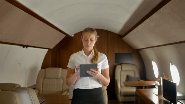 Businesswoman in Air Private Jet Surfing Internet on Tablet PC