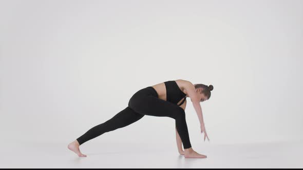 Young Flexible Practicing Trikonasana and Downward Dog Poses Stretching Her Back Over White Studio