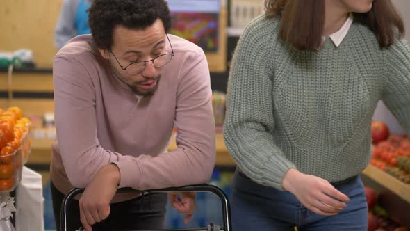 Young Man Looking Sadly at Woman's Choice in Store