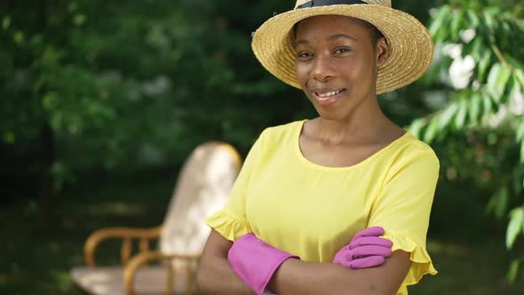 Confident Young African American Woman in Gardening Gloves and Straw Hat Turning Looking at Camera