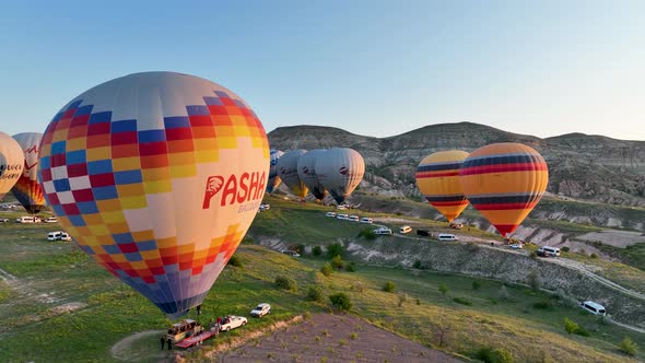 Hot air balloons fly over the mountainous landscape of Cappadocia, Turkey.