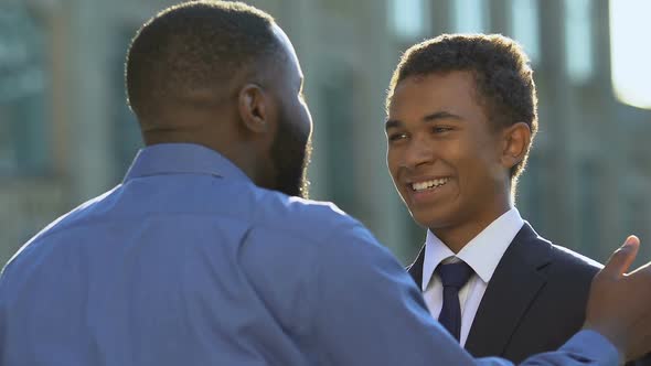 Cheerful African-American Male Hugging Teenage Son in Formal Suit Family Support