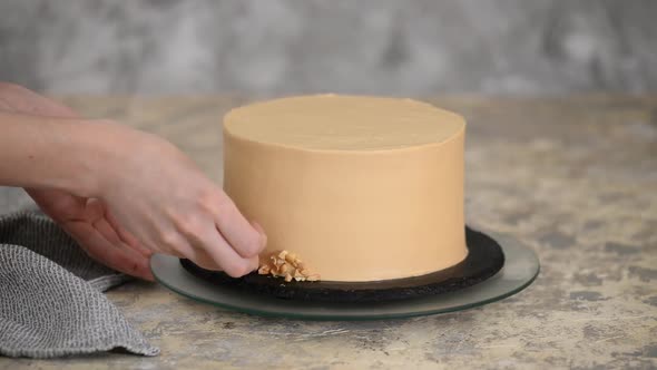 Pastry chef decorating the caramel cake with a peanuts.