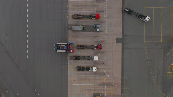 Overhead Top Down Aerial View of a Forklift Moving Cargo From Parked Truck in Cargo Terminal Seaport