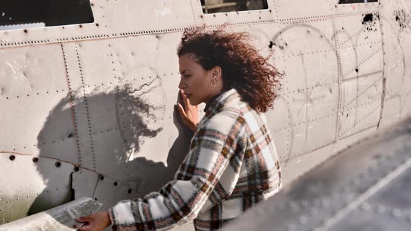 Breathtaking Shot of Female Model Appreciating the Outside of a Plane Wreck