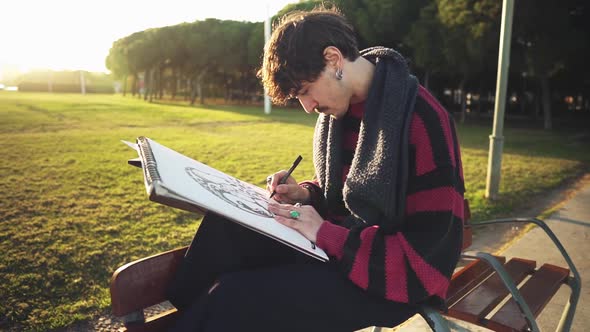 Modern Young Stylish Male Paint Artist Drawing Sketches in Park