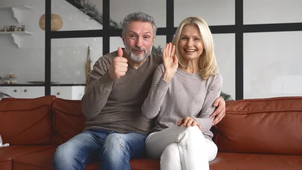 Video Screen with Cheerful Middleaged Couple Looks at the Camera and Waving