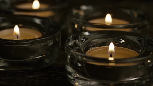 Tea candles with flaming wicks on a wooden background - CANDLES 022