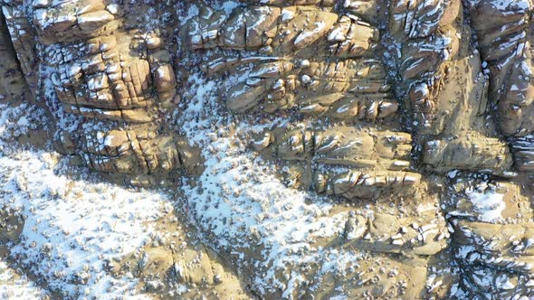 Rocky landscape covered in pure white snow, aerial top down view