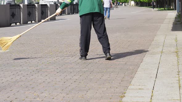 a Janitor Sweeps a Path on the Waterfront with a Broom