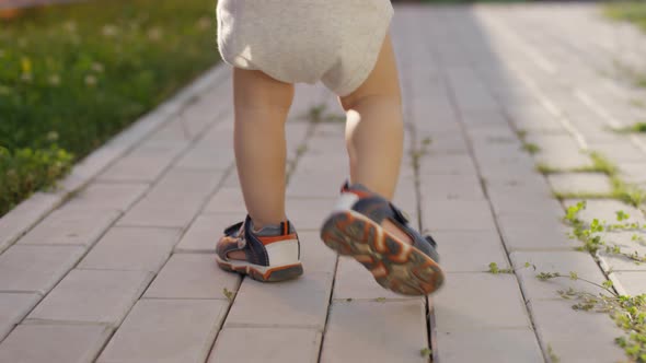 Legs of Unrecognizable Toddler Walking on Footpath Outdoors