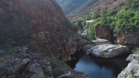 Drone shot flying backwards and up out of mountain gorge with freshwater pools in Karoo.