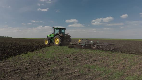 Tractor plows the ground with a plow in the field