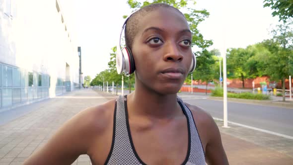 Slow motion shot of young athletic woman with headphones in city