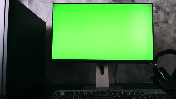 Black computer with green screen monitor on the desk in the dark room at home