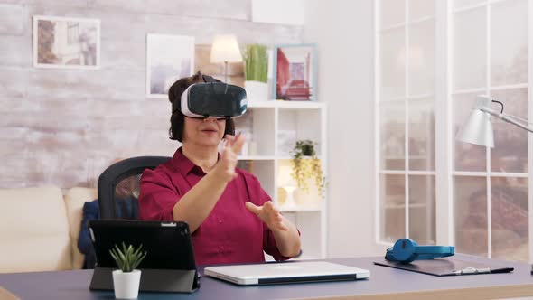 Elderly Age Woman Using Virtual Reality Goggles in Living Room