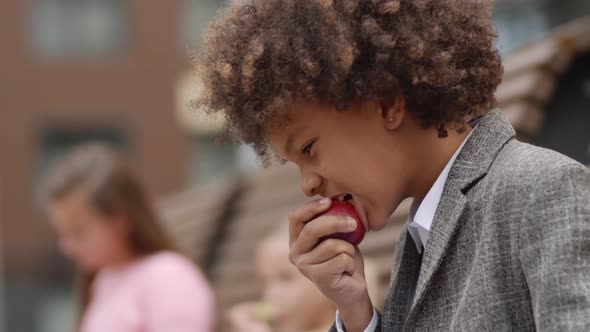 Mixed-race Schoolboy Having Bite Outdoors