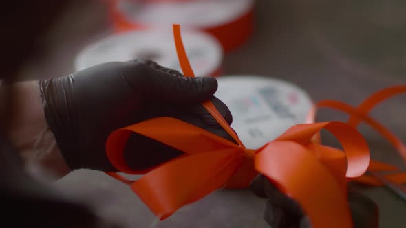 Volunteers at a florist shop prepare bows for bouquets. Close up shot, slow motion.