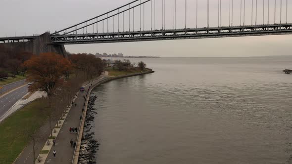 on a cloudy day the drone camera dollys in beside Shore Parkway. The Verrazzano-Narrows Bridge is in