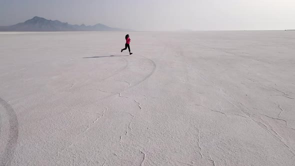 Aerial shot of an Asian woman jogging across the Bonneville Salt Flats flats