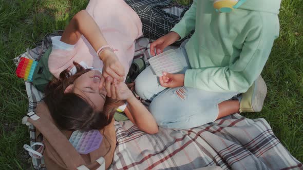 Three Children Relaxing on Blanket in Park