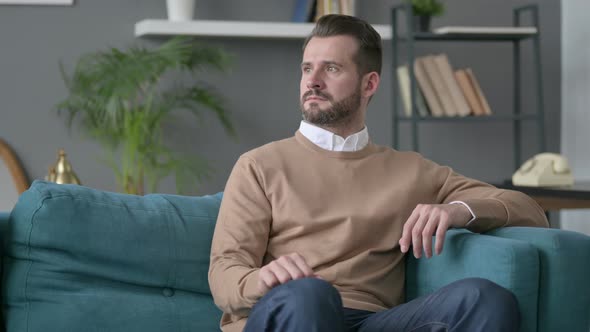 Man Sitting on Sofa Thinking