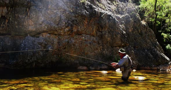 Fisherman fly fishing in river