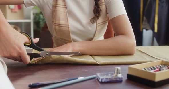 Woman Dressmaker Cutting Fabric with Scissors Closeup Working in Atelier