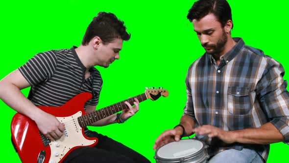 Male musicians singing song while playing guitar and drum