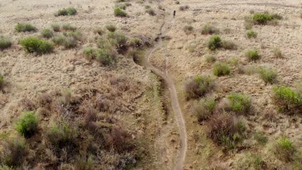 aerial following mountain bikers on a single track in slow motion