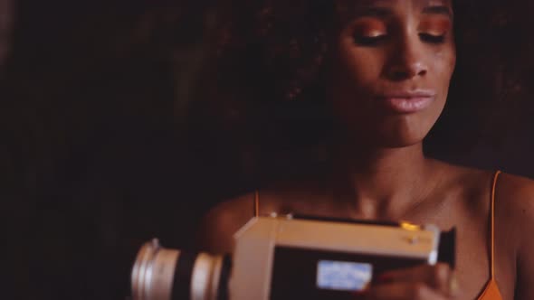 Woman With Afro Hair In Orange Dress Holding Vintage 8Mm Camera